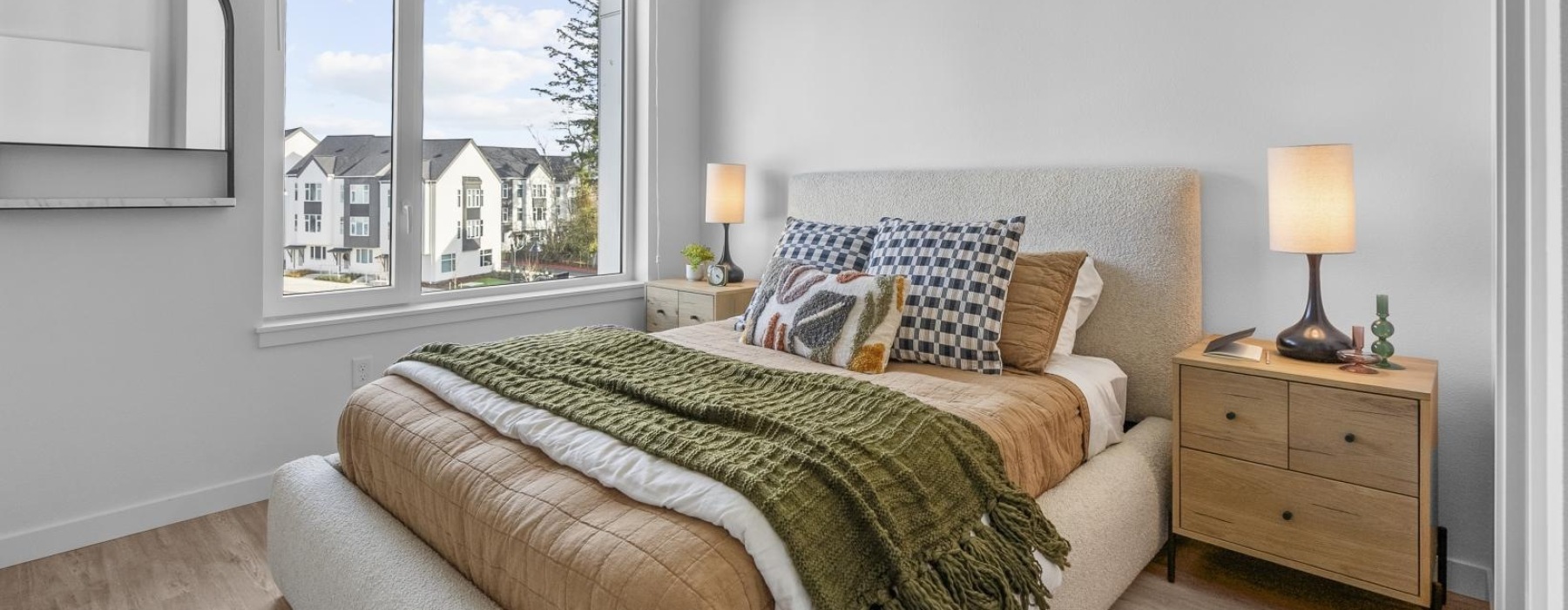 cozy bedroom featuring a neatly made bed, two nightstands, and a large window allowing natural light
